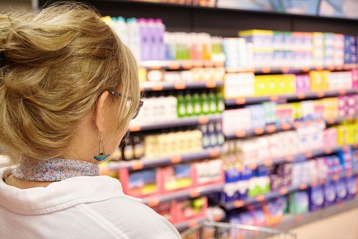 Mujer en el supermercado mirando las etiquetas de los productos para ver los colorantes y conservantes